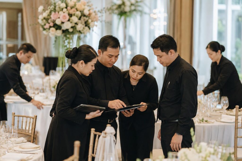Catering team reviews event details while preparing tables inside a refined wedding reception venue