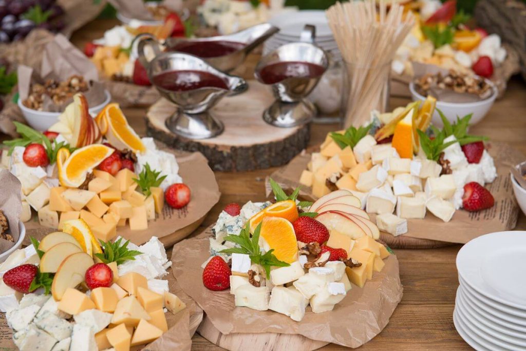 Elegant grazing station with cheeses, fruits, sauces, and plates for an interactive wedding menu setup
