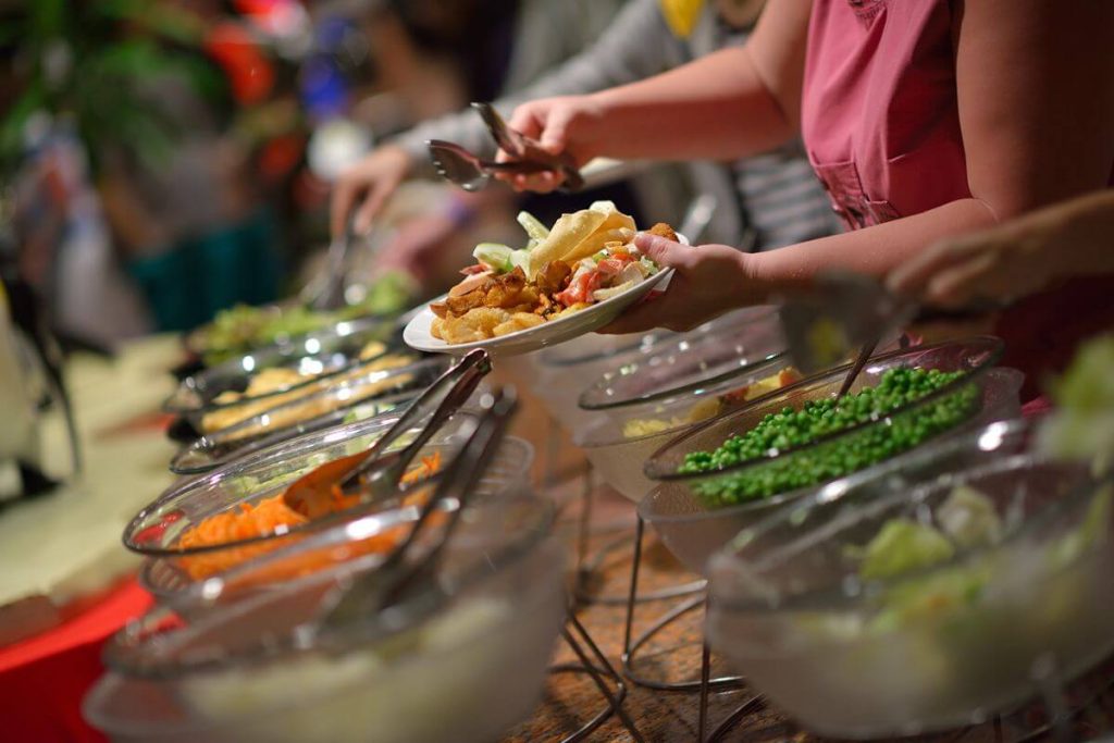 Guests serve themselves from a buffet line with colorful dishes during a debut celebration