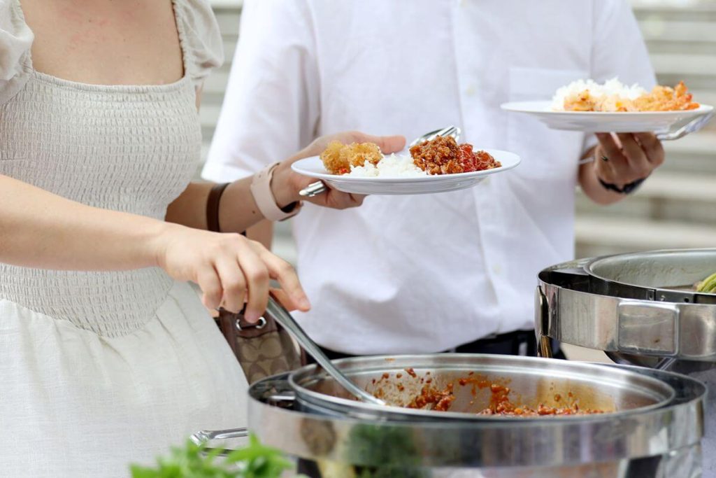 Wedding guests serve themselves familiar comfort dishes from a classic buffet setup