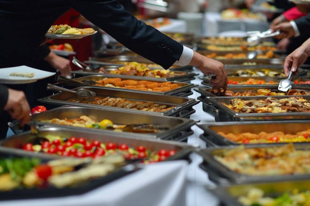 Guests choose dishes from a buffet spread with assorted wedding menu options and serving trays