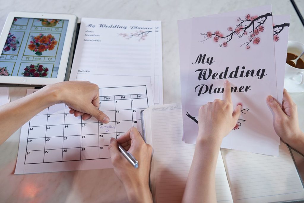 Wedding planning documents, calendar, and notes used to review catering costs, schedules, and package details
